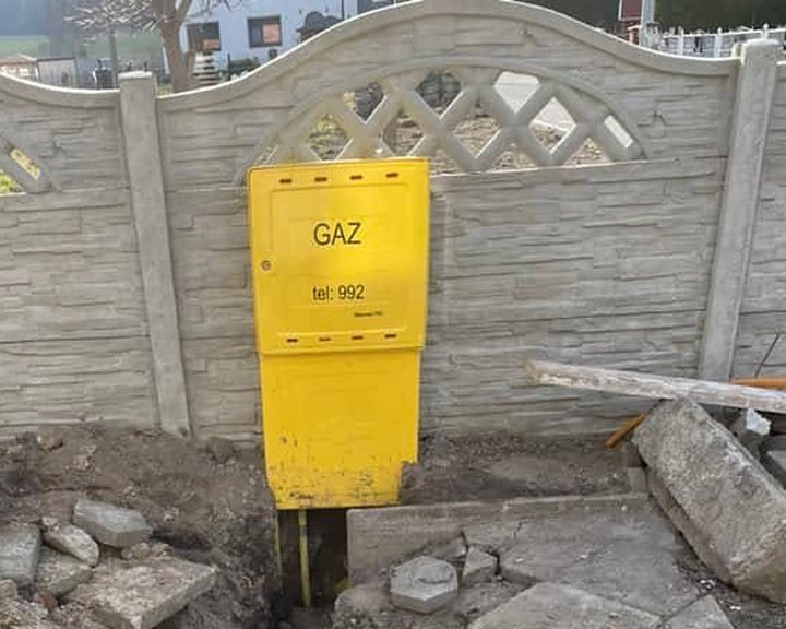 Żółta szafka gazowa przy ogrodzeniu i wykop pod przyłącze